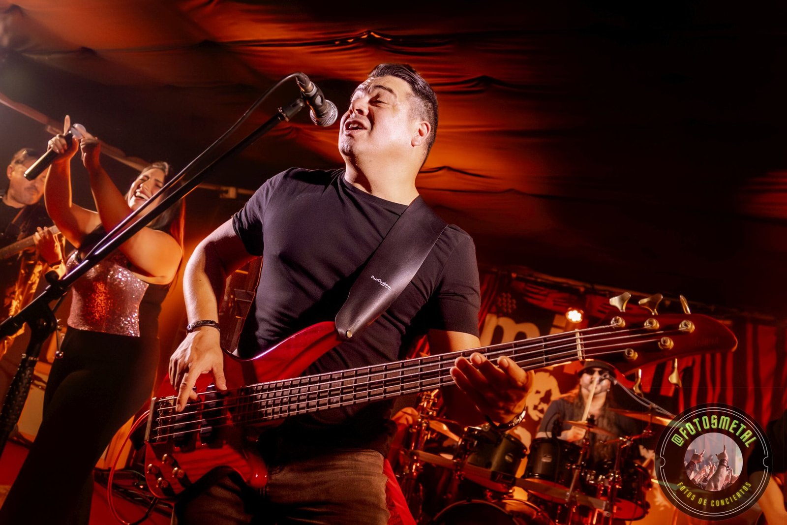 Resumen Editorial: Metal en Vivo – Marzo 2026 14 Cantante con gafas y barba en escenario iluminado de verde apuntando y sosteniendo micrófono.