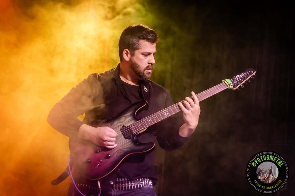 Baterista con chaqueta de cuero tocando batería en escenario iluminado durante concierto.