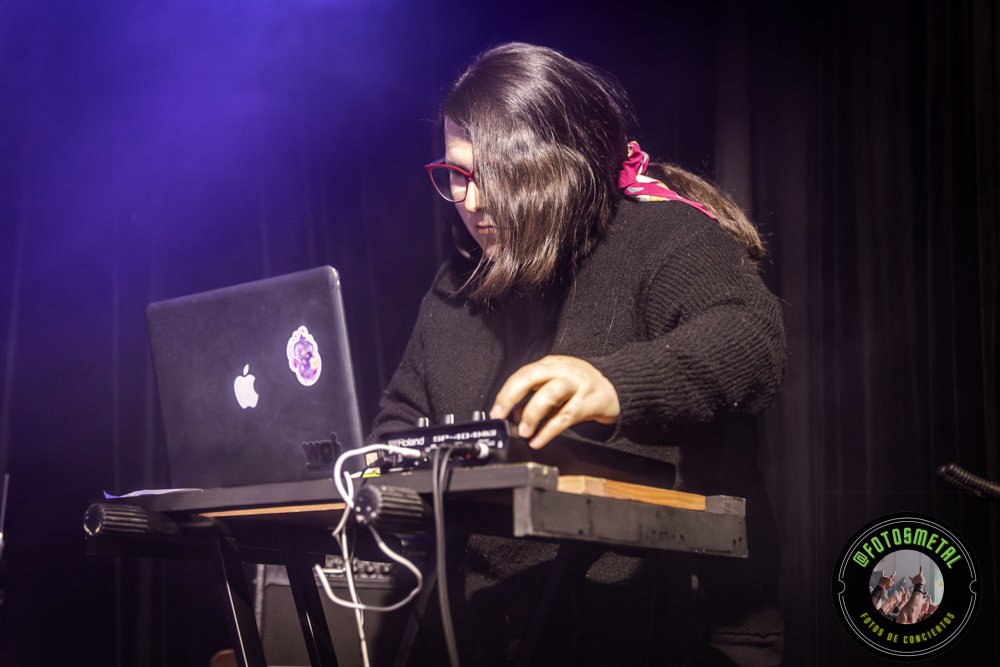 Baterista con chaqueta de cuero tocando batería en escenario iluminado durante concierto.
