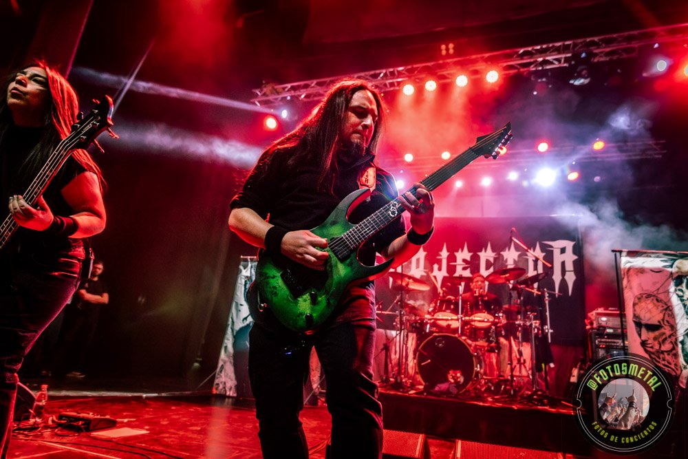 Reseña de The Haunted, Madbrain y Projector en Chile: Furia Sueca y Metal Latino 2 Cantante con gafas y barba en escenario iluminado de verde apuntando y sosteniendo micrófono.