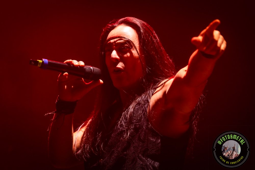Fuego, Demonios y Luz: Helloween 2026 1 Cantante de cabello oscuro sostiene micrófono y señala al público en escenario iluminado en rojo.