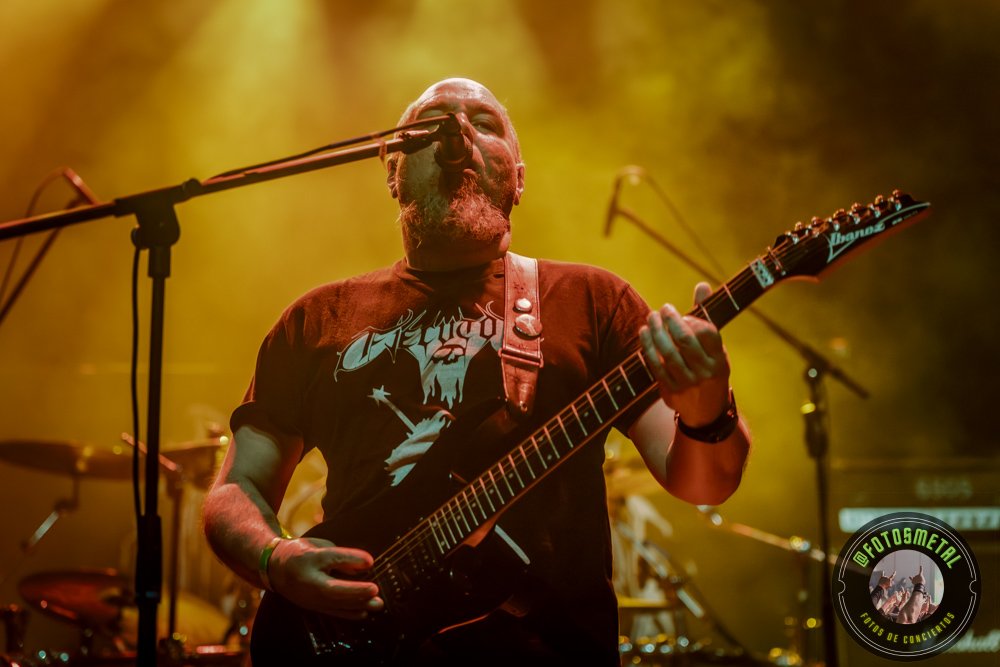 Left to Die en Chile: El eco primitivo del death metal choca en el Teatro Cariola 1 Hombre mayor con barba toca guitarra eléctrica en escenario iluminado en tonos amarillos.