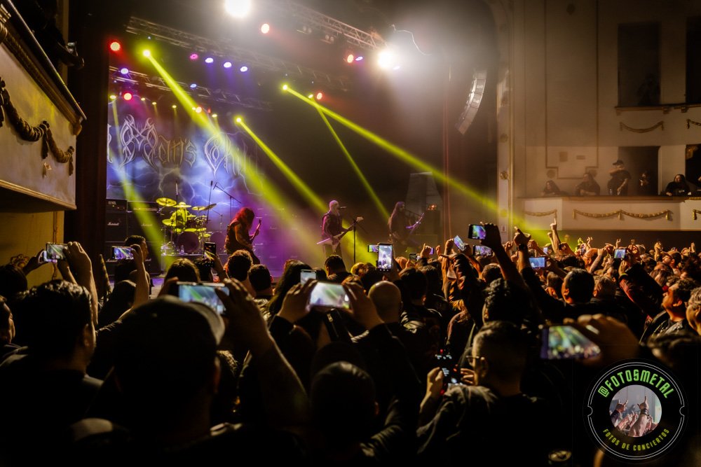 Old Man’s Child en Chile 2026: Reseña y Setlist en el Cariola 13 Cantante con gafas y barba en escenario iluminado de verde apuntando y sosteniendo micrófono.