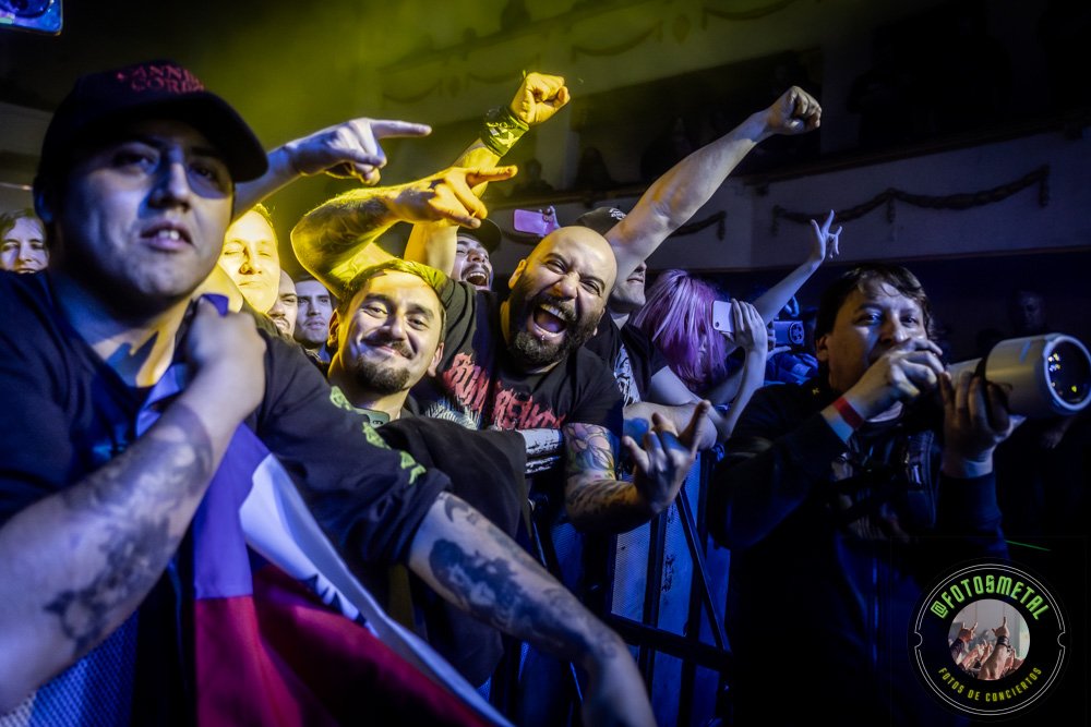 Old Man’s Child en Chile 2026: Reseña y Setlist en el Cariola 12 Grupo de aficionados en primera fila durante un concierto, sonrisa, brazos en alto y fotógrafo con cámara.