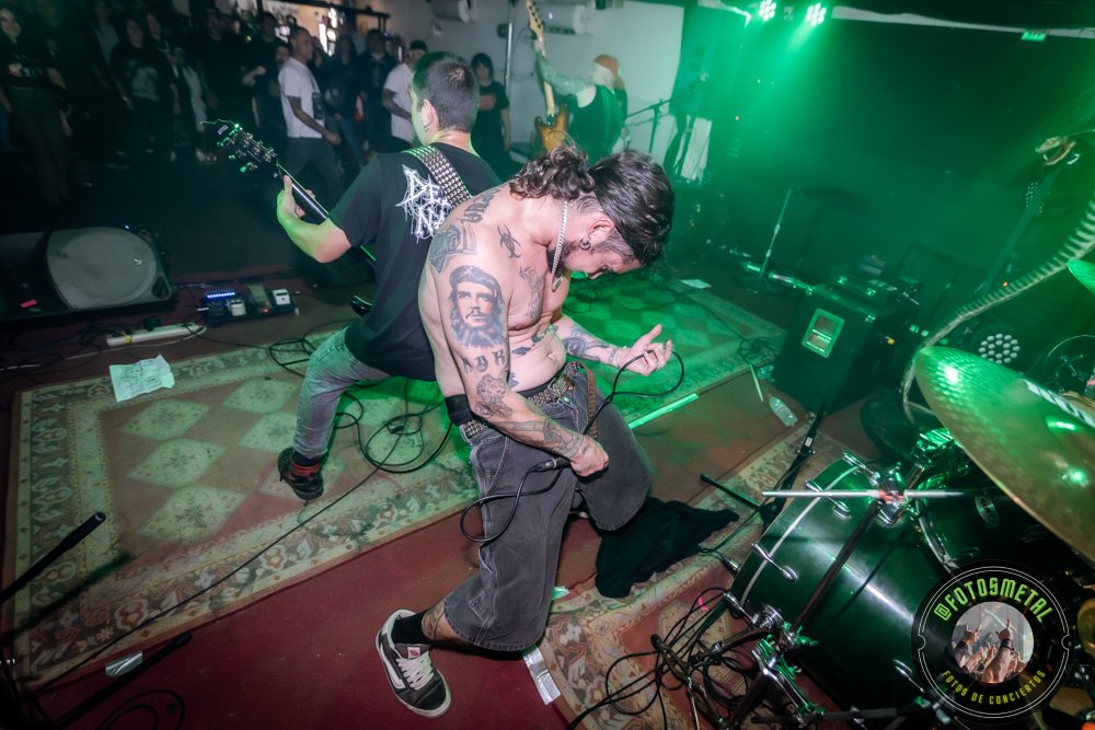 Sobernot y Dezaztre Natural en MiBar: Noche de groove, crossover y mosh intenso 5 Músico sin camisa con tatuajes, guitarra en mano, en escenario pequeño con público.